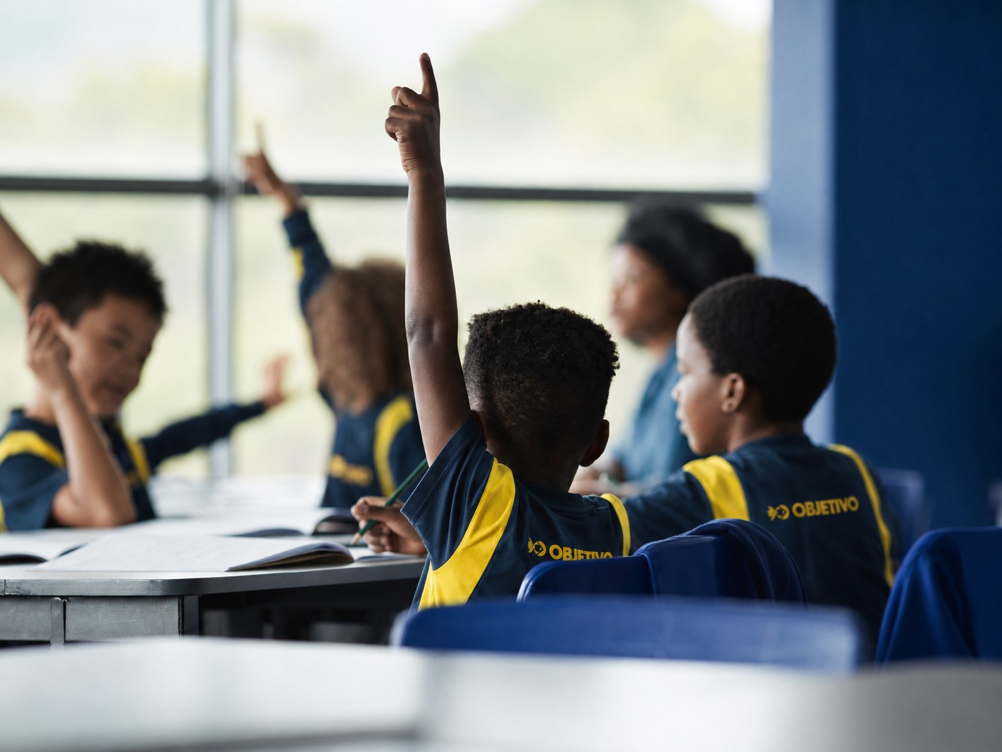 Alunos do Colégio Ipê participando da aula, com as mãos levantadas